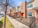 Street view of modern townhomes with brick and siding exteriors and black metal fences at 7323 Lowell Blvd, Westminster, CO 80030