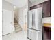 Spacious kitchen with stainless steel refrigerator and white tiled floor and staircase at 7323 Lowell Blvd, Westminster, CO 80030