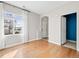 Bright living room with hardwood floors, window with white curtains, and adjacent hallway at 7323 Lowell Blvd, Westminster, CO 80030