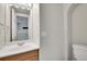 Bright bathroom featuring a vanity with a wooden base cabinet and a white sink, alongside a toilet and arched wall alcove at 8848 Prickly Pear Cir, Parker, CO 80134