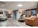Open basement with a wood accent wall, bar seating, laminate floors and tan leather sofas at 9658 Coronado Ct, Parker, CO 80134