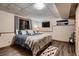 Cozy bedroom featuring a queen bed with many pillows, wood floors, and a flat screen television at 9658 Coronado Ct, Parker, CO 80134