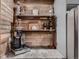 A stylish coffee bar area with wood plank backsplash, floating shelves, and modern appliances at 9658 Coronado Ct, Parker, CO 80134