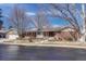 Single-story red brick home with red shutters on a lot with snow, trees, and a sidewalk at 3905 S Jersey St, Denver, CO 80237