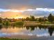 Scenic view of a tranquil pond reflecting a vibrant sunset with houses visible on the opposite shore at 254 Lead Queen Dr, Castle Rock, CO 80108