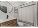 This bathroom features a wood vanity, modern sink, shower with curtain, and round mirror at 3107 S Nepal Way, Aurora, CO 80013