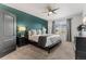 A well-lit bedroom with a teal accent wall, soft carpet, ceiling fan, and natural light at 3107 S Nepal Way, Aurora, CO 80013