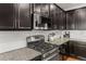 Close-up of kitchen with stainless steel range, microwave, granite counters, and dark cabinets at 3107 S Nepal Way, Aurora, CO 80013