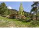 Beautiful home exterior surrounded by lush greenery, featuring a well-manicured lawn, trees, and natural landscaping at 107 Elk Dr, Evergreen, CO 80439