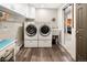 Efficient laundry room featuring a side-by-side washer and dryer, ample storage cabinets, and wood-look flooring at 107 Elk Dr, Evergreen, CO 80439
