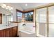 A bright bathroom featuring a jetted tub under a window and a tiled shower with glass door at 8187 N Pinewood Dr, Castle Rock, CO 80108