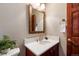 Bathroom with a wooden vanity, white countertop, decorative mirror and brass fixtures in a warm setting at 8187 N Pinewood Dr, Castle Rock, CO 80108