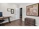 A home office offers a desk, artwork, dark wood floors, and access to another room with a dark wall at 5336 Trails Edge Ln, Castle Rock, CO 80104