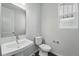 Clean, well-lit half bathroom with white fixtures, a pedestal sink, and a window, perfect for guests at 9374 Quartz St, Arvada, CO 80007