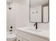 Modern bathroom featuring white vanity, black fixtures, a framed mirror, and tiled shower at 4135 Benton Street, Denver, CO 80212