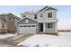 Two-story house with gray and white siding, a two-car garage, and a snowy front yard at 811 Goodrich Peak St, Erie, CO 80516