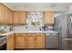 Kitchen showcasing ample oak cabinetry, stainless-steel appliances, light countertops, and natural light from a window at 1774 S Dover Way, Lakewood, CO 80232