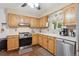A well-lit kitchen featuring oak cabinets, stainless steel dishwasher, and a window that overlooks a lush backyard at 1774 S Dover Way, Lakewood, CO 80232