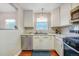 White kitchen with stainless appliances, stone countertops, and a sunny window at 4374 S Washington St, Englewood, CO 80113