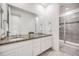 Bathroom featuring dual sinks with granite countertop, modern white cabinetry, and a tiled walk-in shower at 10387 Harrisburg St, Parker, CO 80134