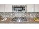 Modern kitchen with stainless steel gas cooktop, granite countertops, mosaic backsplash, and stylish microwave at 10387 Harrisburg St, Parker, CO 80134