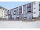 Modern townhome with gray and black siding, multiple balconies and snow-covered ground at 5531 W 11Th Pl, Lakewood, CO 80214