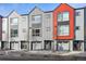 Modern townhomes featuring gray and red exteriors with attached garages on a tree-lined street at 5531 W 11Th Pl, Lakewood, CO 80214