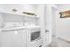 Well-lit laundry room with white washer and dryer, and shelving for storage at 5387 Pierson Ct, Wheat Ridge, CO 80033
