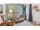Charming Bedroom featuring a wooden crib, rocking chair, green walls, and soft lighting at 10360 E 57Th Pl, Denver, CO 80238