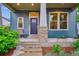 Inviting front porch with blue siding, stone accents, and a cozy seating area at 10360 E 57Th Pl, Denver, CO 80238