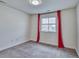 Neutral bedroom with red curtains, gray carpet, and natural light through the window at 9551 Eldora St, Arvada, CO 80007