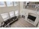 Cozy living room with a fireplace, light wood floors, large windows, and a view of the upstairs balcony at 10058 Glenstone Cir, Highlands Ranch, CO 80130