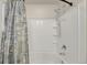 Close-up of a bathtub and shower combo with a seashell-themed curtain at 47349 Lily Ave, Bennett, CO 80102