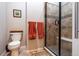 Bathroom includes tiled walk-in shower, a toilet with shelving and two orange-colored towels at 24998 E Alder Dr, Aurora, CO 80016