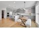 Open kitchen and dining area boasts gray cabinets, stainless appliances, an island, and a rustic dining table at 10770 Hillrose St, Parker, CO 80134