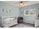 Cozy Bedroom with light blue walls, a white crib, comfortable chair, and a well-lit window at 11446 W 105Th Dr, Broomfield, CO 80021