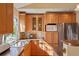 Bright kitchen with natural wood cabinets, stainless steel refrigerator, and a view from the window over the sink at 11446 W 105Th Dr, Broomfield, CO 80021