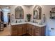 Bathroom with double sinks, wooden cabinets, granite countertops, and decorative mirrors at 10640 W 46Th Ave, Wheat Ridge, CO 80033