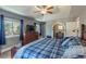 A bright bedroom with a blue plaid bedspread, a ceiling fan, and a dresser with a TV at 10640 W 46Th Ave, Wheat Ridge, CO 80033