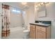 Well-lit bathroom with white tiled shower-tub, tan vanity, modern mirror and sink at 12235 E Kentucky Ave, Aurora, CO 80012