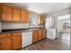 Kitchen with wood cabinets, white appliances, and laundry area at 3100 Gray St, Denver, CO 80214