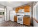 Kitchen with wood cabinets, white appliances and view into living room at 3100 Gray St, Denver, CO 80214