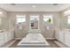 Bright bathroom featuring double sinks, a soaking tub with a marble surround, and wooden floors at 8993 Stonecrest Way, Highlands Ranch, CO 80129