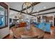 Open-concept living room with wood beams, modern lighting, fireplace, hardwood flooring, and blue kitchen island at 19336 Queens Crescent Way, Monument, CO 80132