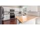 Modern kitchen featuring white cabinets, wood countertops, stainless steel appliances, and a subway tile backsplash at 10438 Olathe Way, Commerce City, CO 80022
