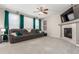 Comfortable living room featuring a plush gray sofa, fireplace, large windows with green curtains, and a ceiling fan at 10438 Olathe Way, Commerce City, CO 80022