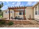 Outdoor patio with a pergola, stone seating, landscaping, and a table with chairs at 5603 Van Bibber Ct, Golden, CO 80403