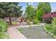 Backyard featuring lush landscaping, a brick pathway, and an inviting outdoor seating area with a fire pit at 998 S Leyden St, Denver, CO 80224