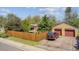 Property showcasing a detached garage, fenced yard, mature trees, and street view at 998 S Leyden St, Denver, CO 80224
