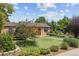 Charming one-story home with a well-manicured lawn, lush landscaping, and a bright red front door at 998 S Leyden St, Denver, CO 80224